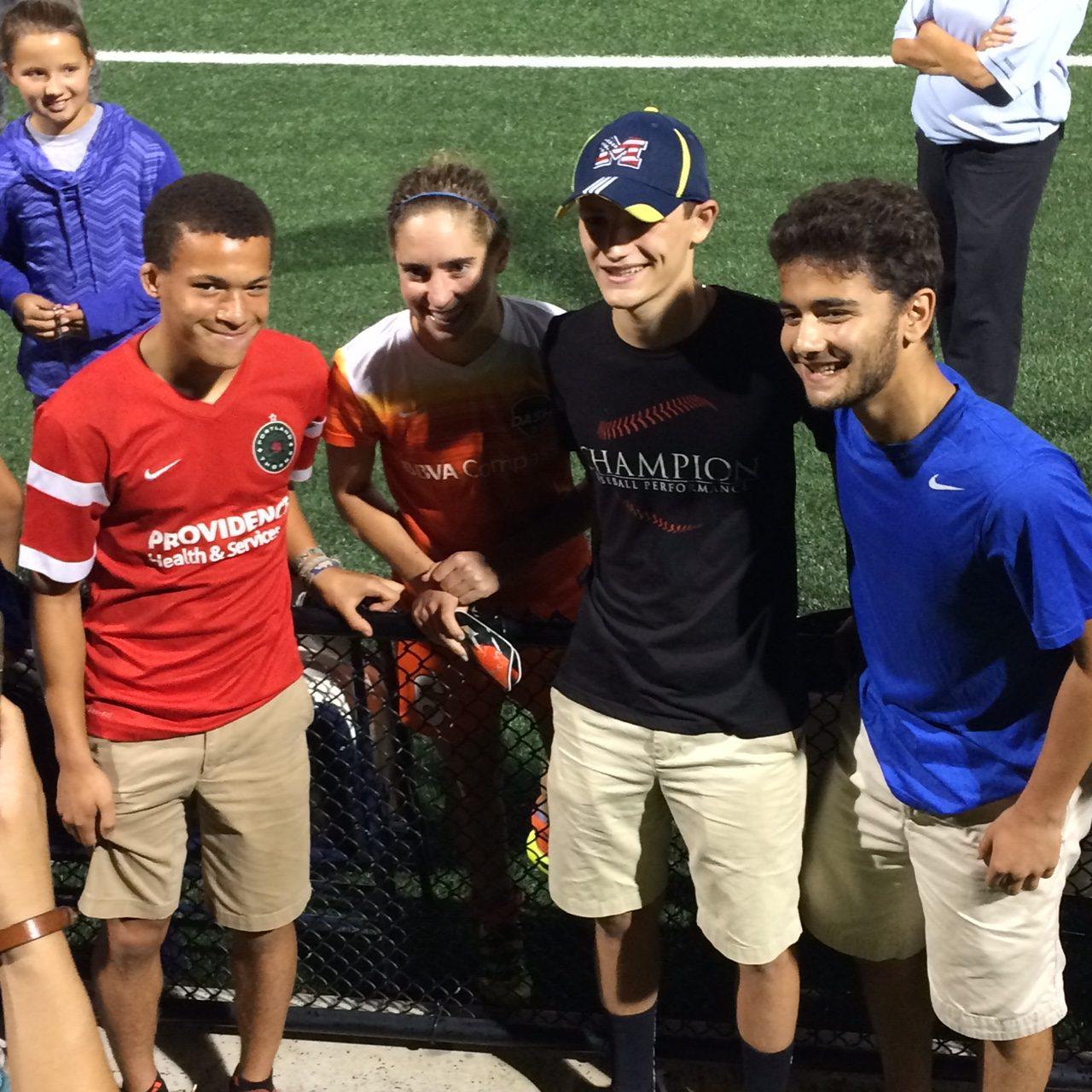 Bennett Walkes, Cam Dubin, and Mike Ryter of Newton South's Denebola snap a post-game photo with Houston Dash/US women's national team midfielder Morgan Brian after the game at Harvard's Jordan Field on Aug. 31. 
