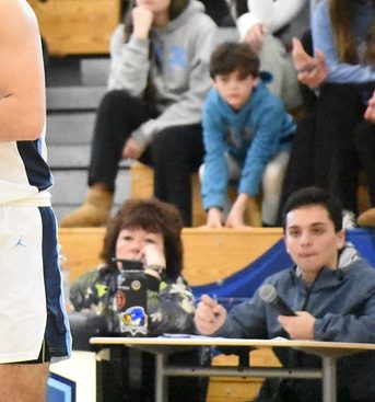 Ryan Martin (blue jacket, bottom right) watches on from his seat as Public Service Announcer while Franklin Boys Varsity Basketball hosts Bridgewater-Raynham.